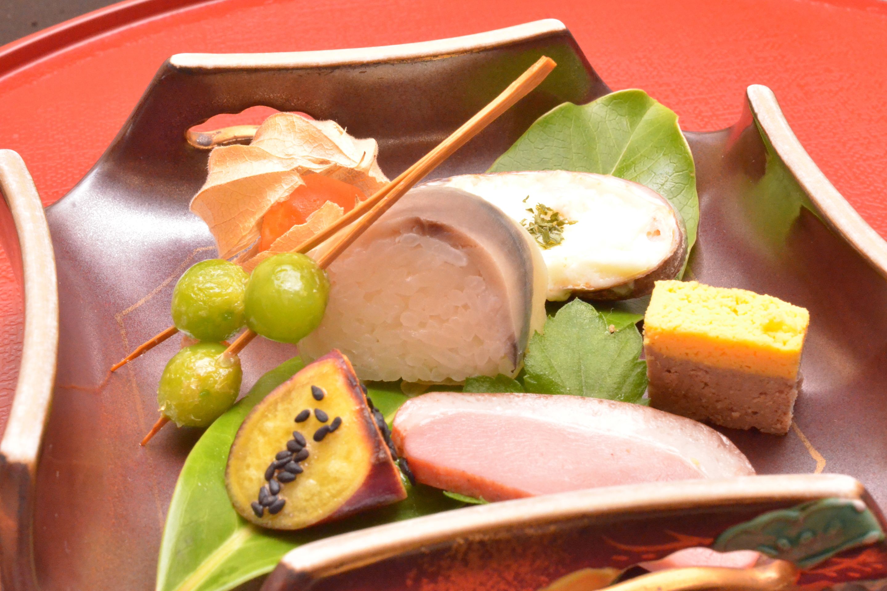 A traditional Japanese dish with various items including sushi, pickled vegetables, and a piece of meat on a ceramic plate.