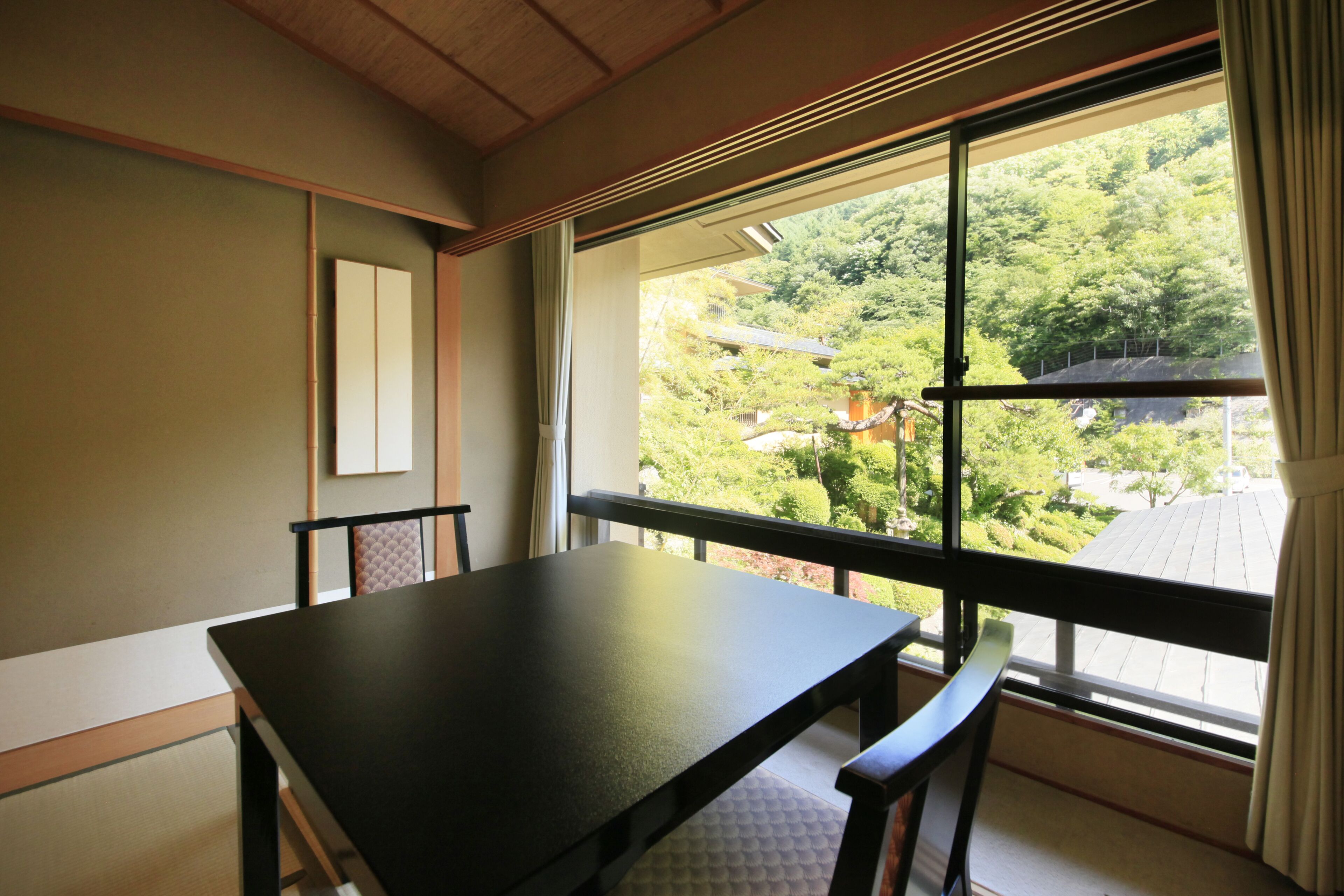 Una habitación con un ventanal grande, una mesa de madera y dos sillas.