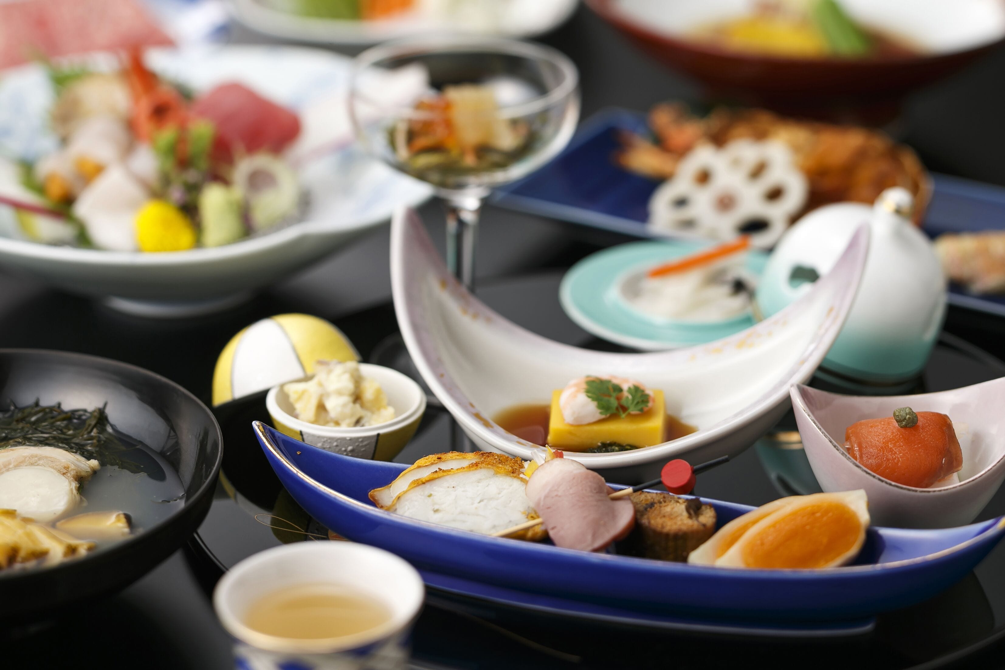 A variety of dishes on a table, including sushi, sashimi, and other Asian cuisine.