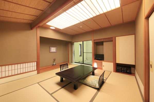 Una habitación japonesa tradicional con suelo de tatami, una mesa baja y puertas correderas.