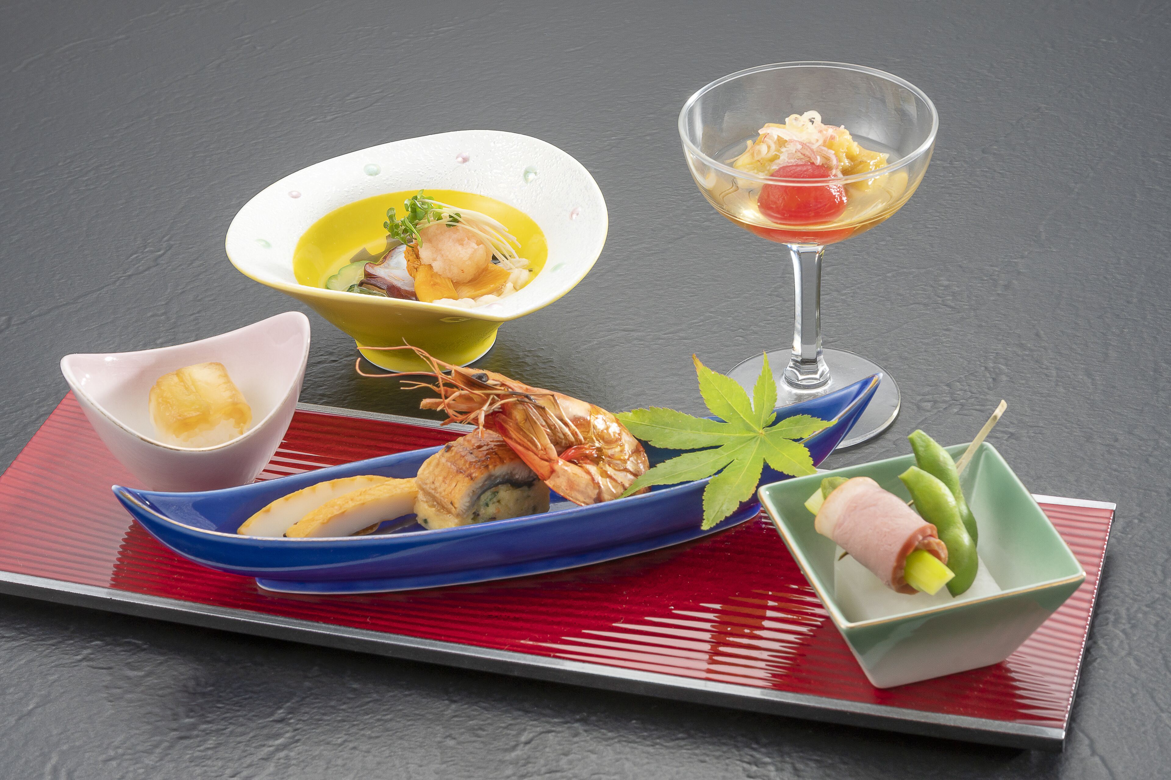 A variety of Japanese dishes on a table with a red placemat.