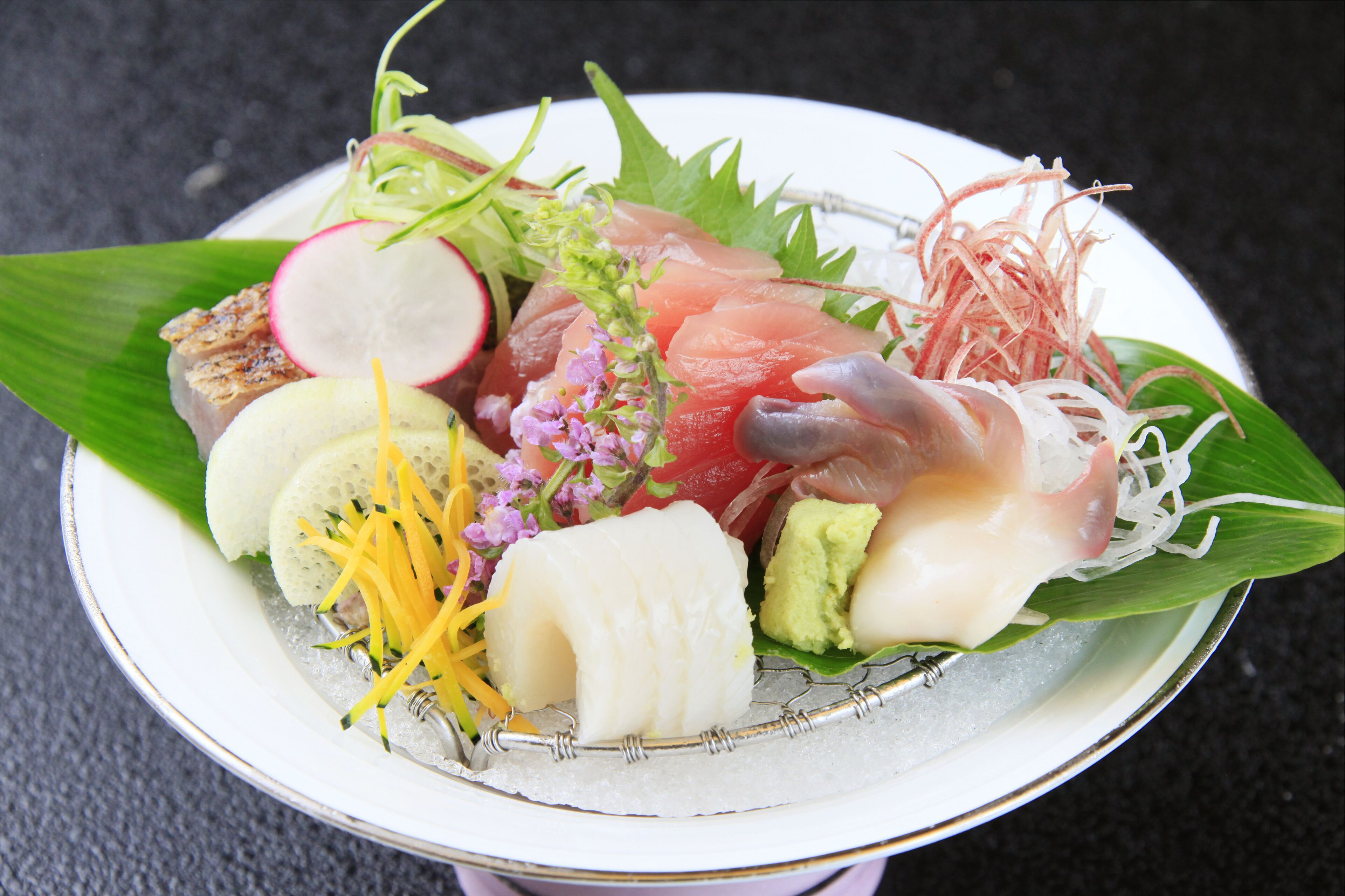 A plate of sushi with various toppings including fish, avocado, and vegetables.