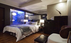 A modern hotel room with a large bed, a desk, a wardrobe, and a view of a cityscape through a large window. - Golden Hotspring Hotel (Taipei)