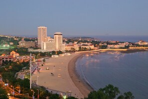 A coastal cityscape with a beach, high-rise buildings, and a promenade.