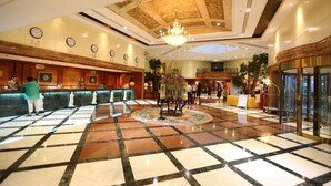 A lobby with a check-in counter, a chandelier, and a tiled floor. - Huiquan Dynasty Hotel (Qingdao)