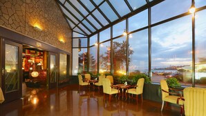 A spacious lobby with a high ceiling, large windows, and a view of the cityscape. - Huiquan Dynasty Hotel (Qingdao)