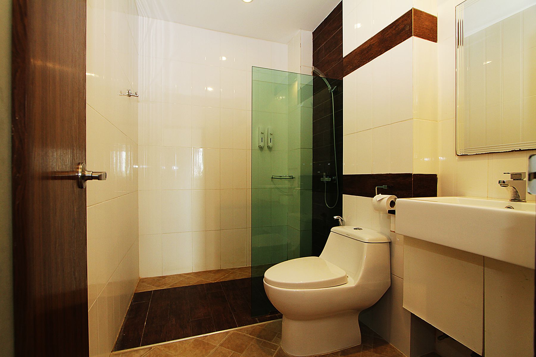 Un baño moderno con cabina de ducha de vidrio, un inodoro blanco y un tocador con espejo.