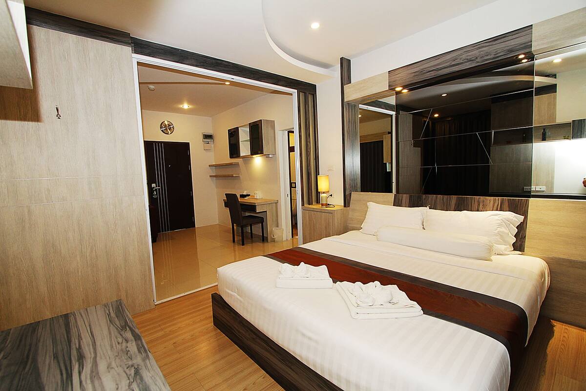 Une chambre d’hôtel moderne avec un grand lit, un bureau et un miroir.