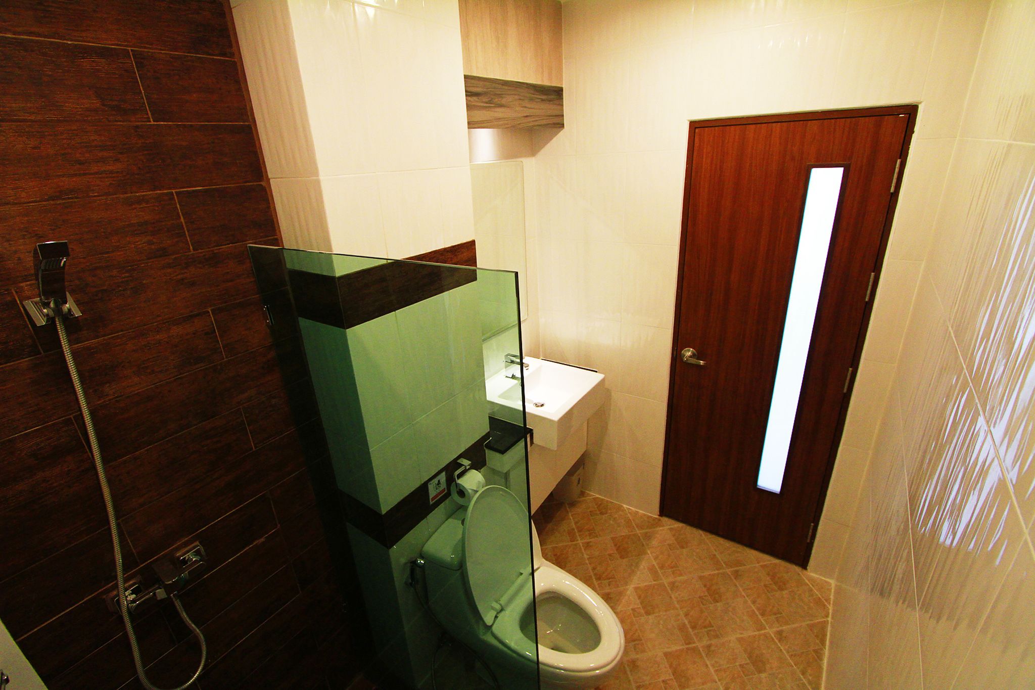 A bathroom with a glass shower enclosure, a toilet, and a sink.