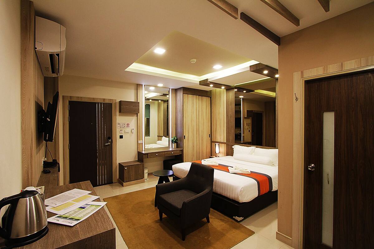 Une chambre d’hôtel avec un lit, un bureau, une chaise, un miroir et une porte.