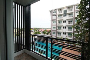 Ein Balkon mit Blick auf ein Schwimmbecken und ein mehrgeschossiges Gebäude im Hintergrund.