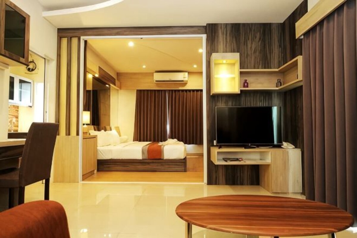 Una habitación de hotel con cama, televisión, escritorio y silla.
