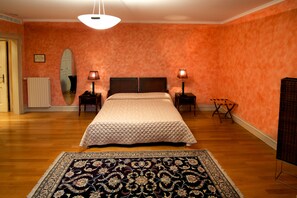 A bedroom with a bed, two bedside tables with lamps, a radiator, a mirror, and a patterned rug. - Radici Resort (Mirabella Eclano)