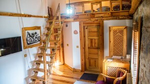 A rustic wooden interior with a wooden staircase, a door, a chair, and a small table with a lamp. - Mogla Tashan Boutique Otel (Mugla)