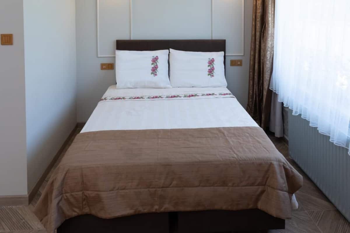 A hotel room with a large bed, two wall-mounted lights, and a window with curtains.