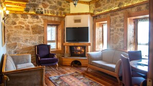 A cozy room with stone walls, a fireplace, a television, and comfortable seating. - Mogla Tashan Boutique Otel (Mugla)