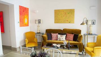 A living room with a mustard-colored sofa, yellow armchairs, and a coffee table with decorative items.