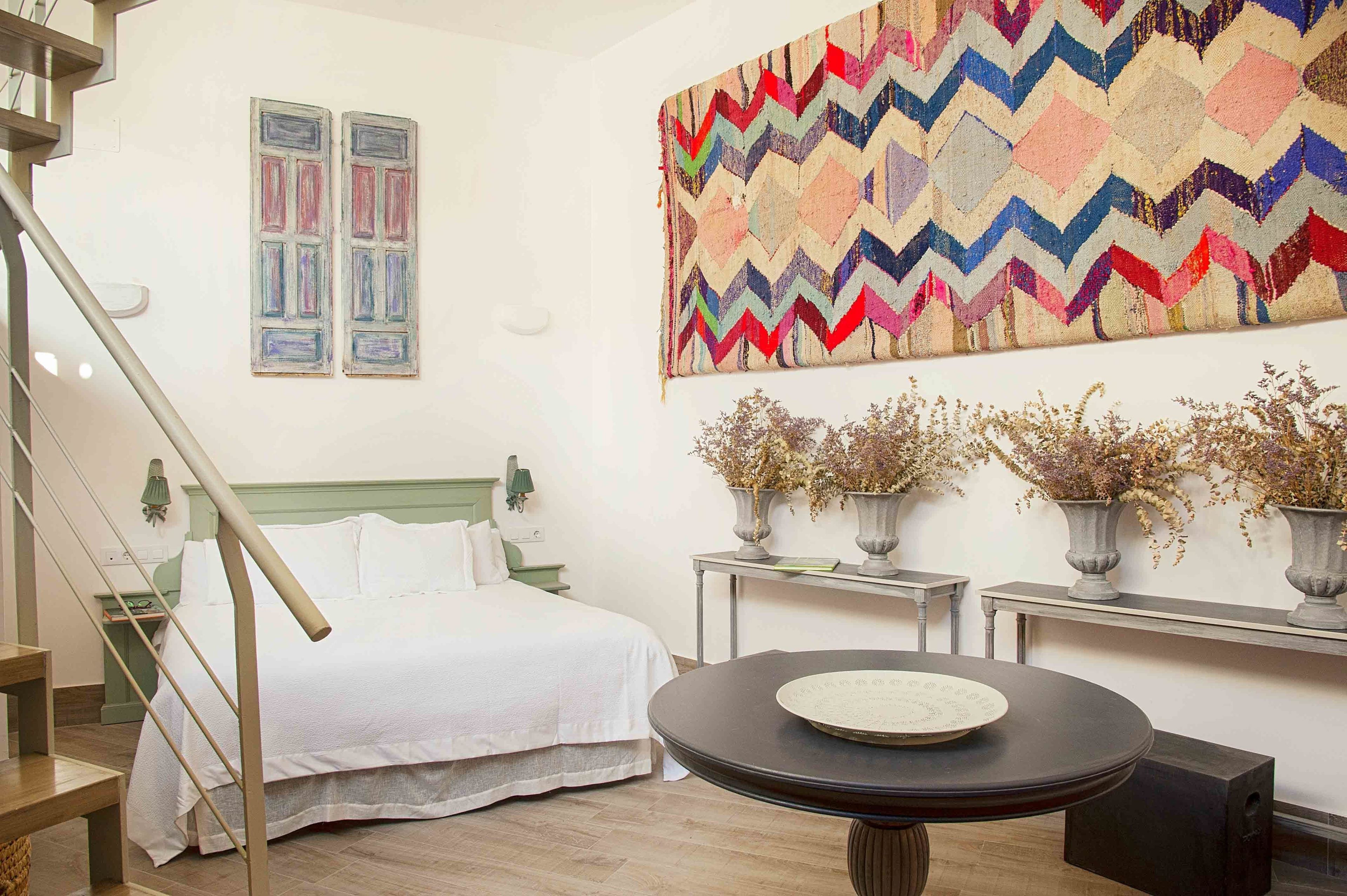 A bedroom with a bed, a round table, and a staircase.