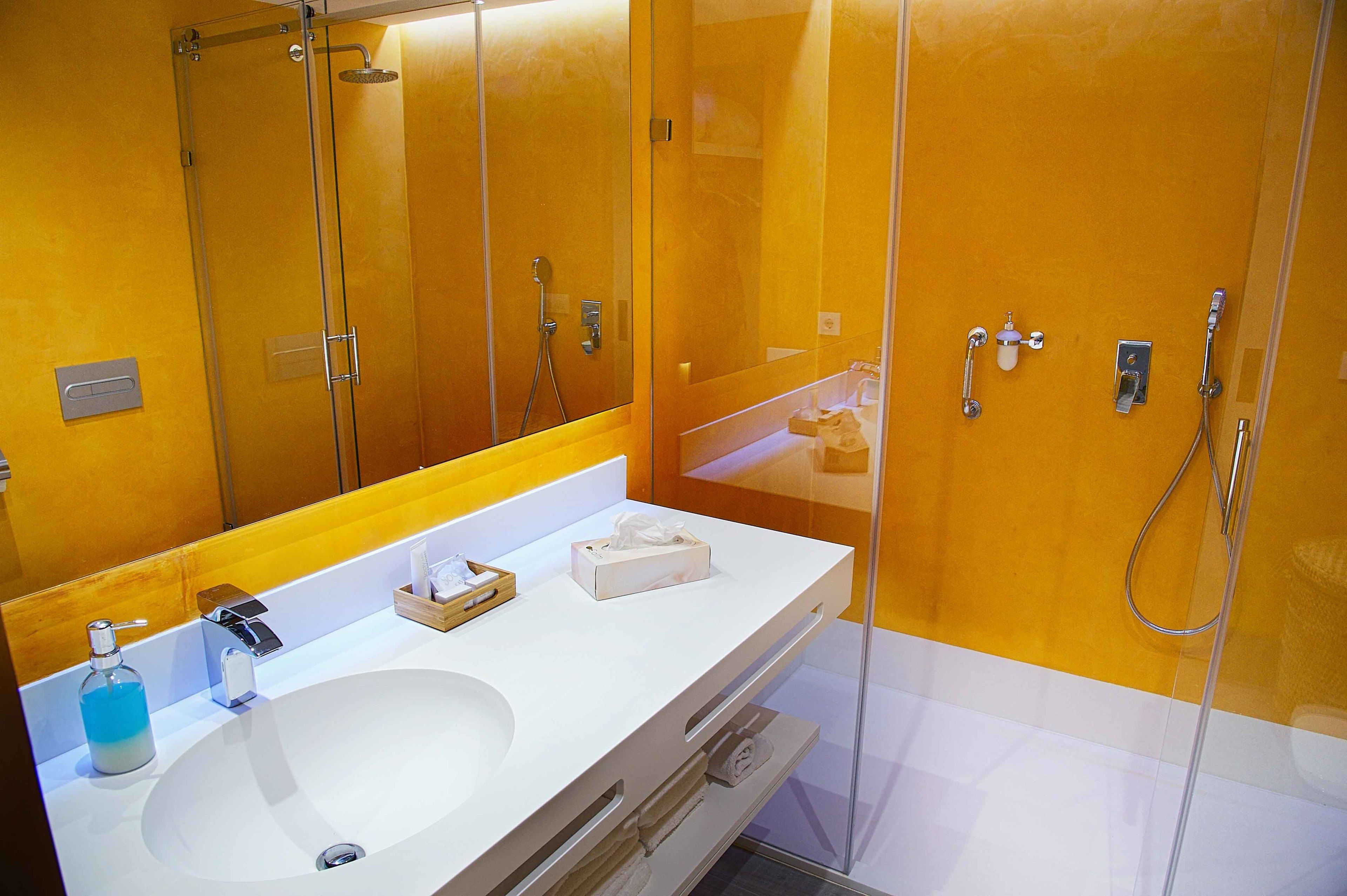 A bathroom with a white sink, a mirror, and a glass shower enclosure.