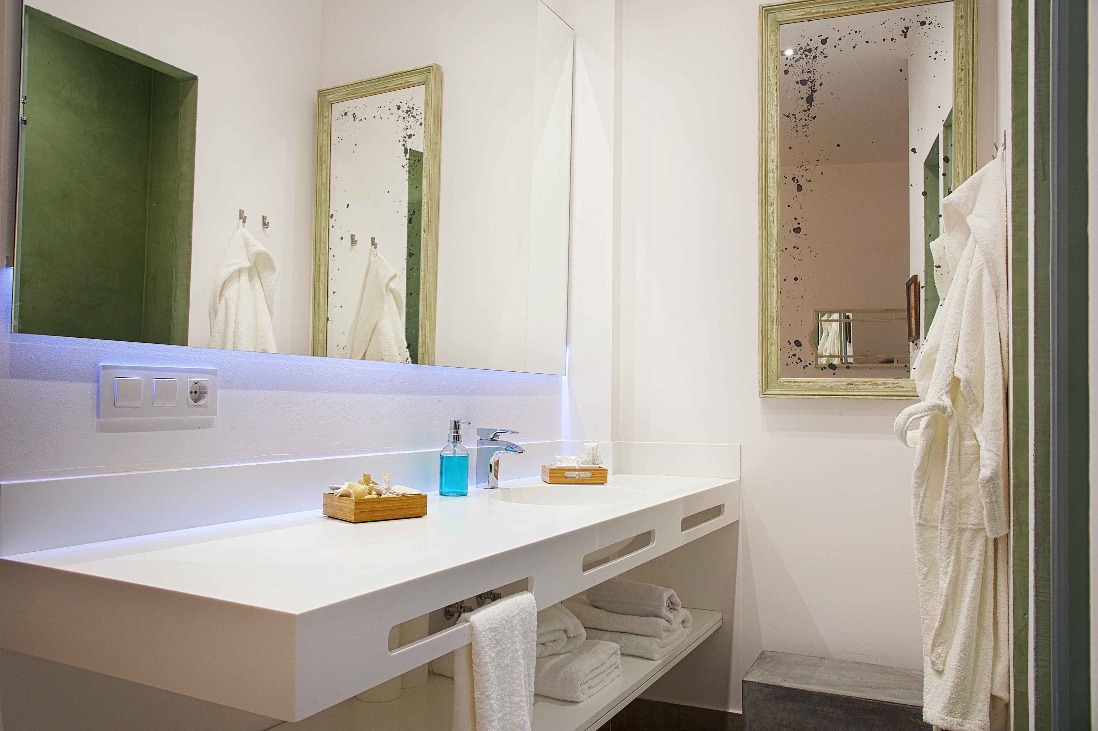 A modern bathroom with a white vanity, two mirrors, and a towel rack.