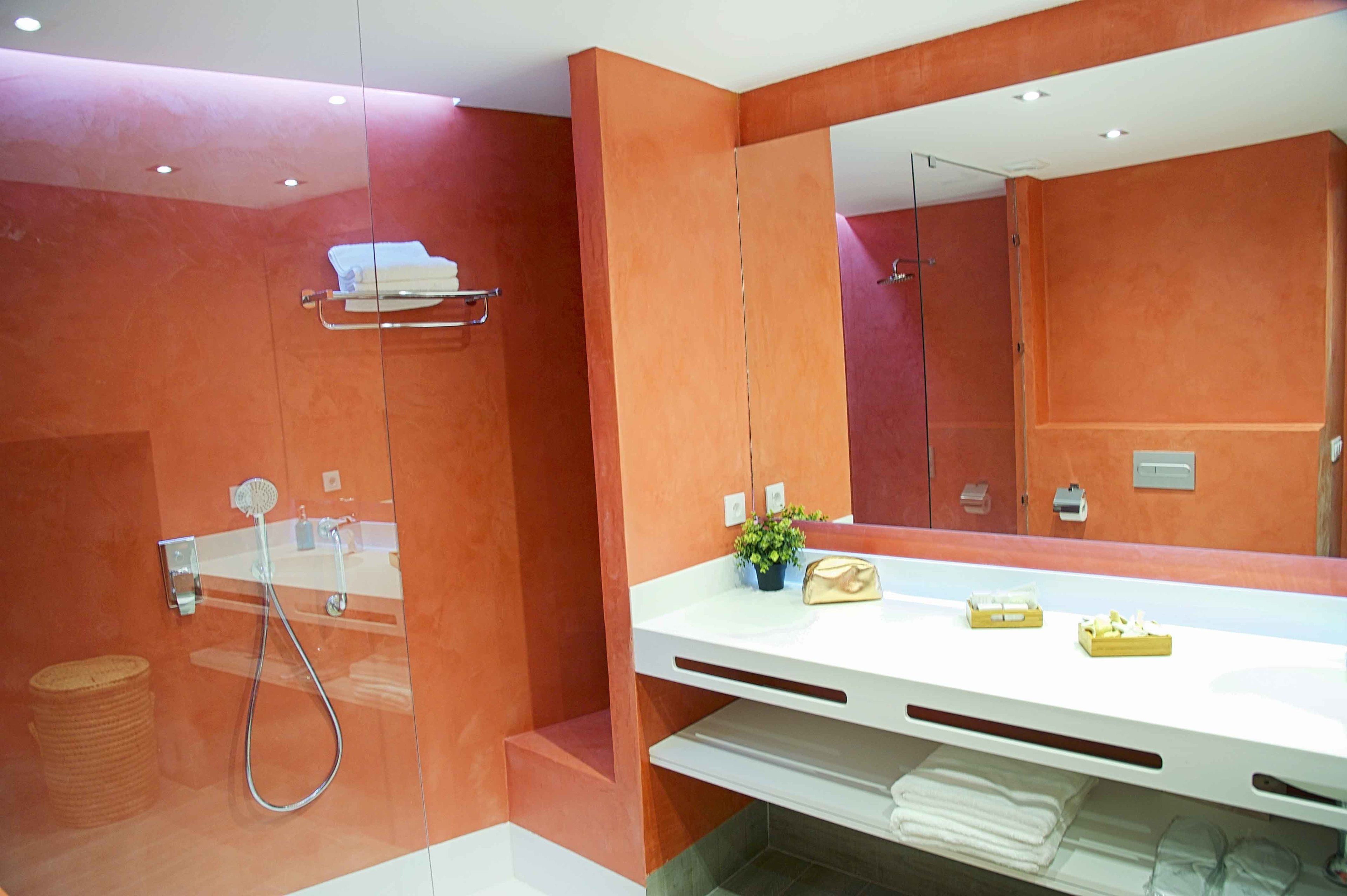 A modern bathroom with a large mirror, a white vanity, and a shower area.