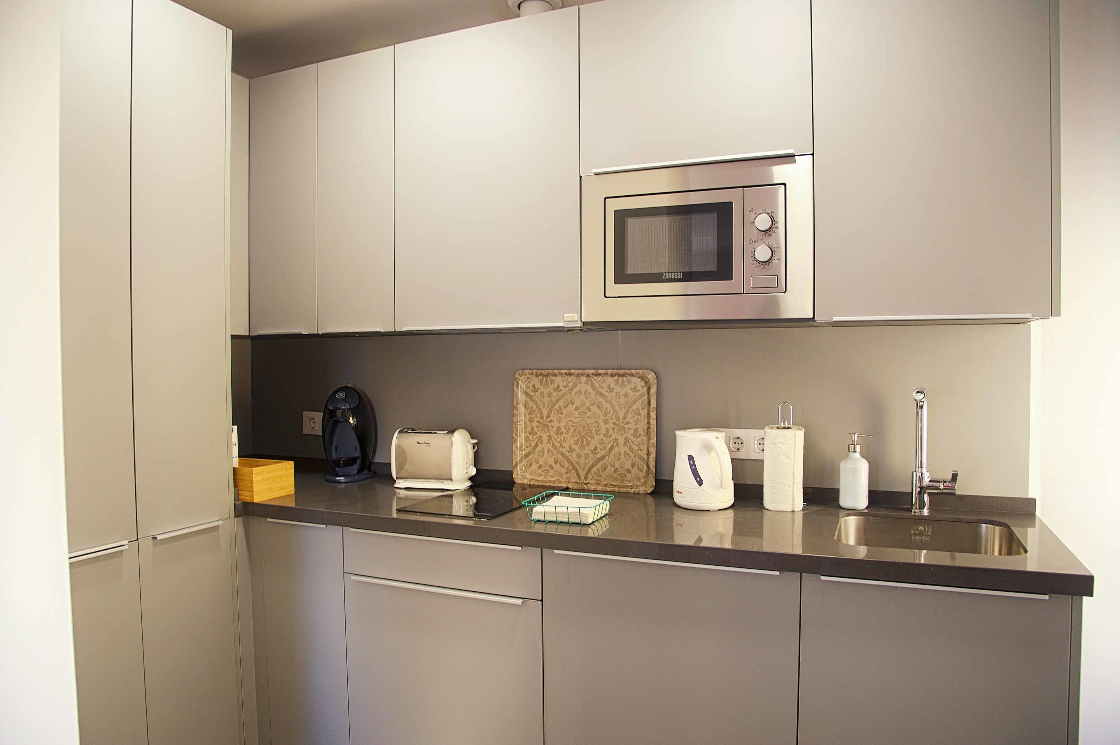 A modern kitchen with stainless steel appliances, a coffee maker, a toaster, and a kettle.