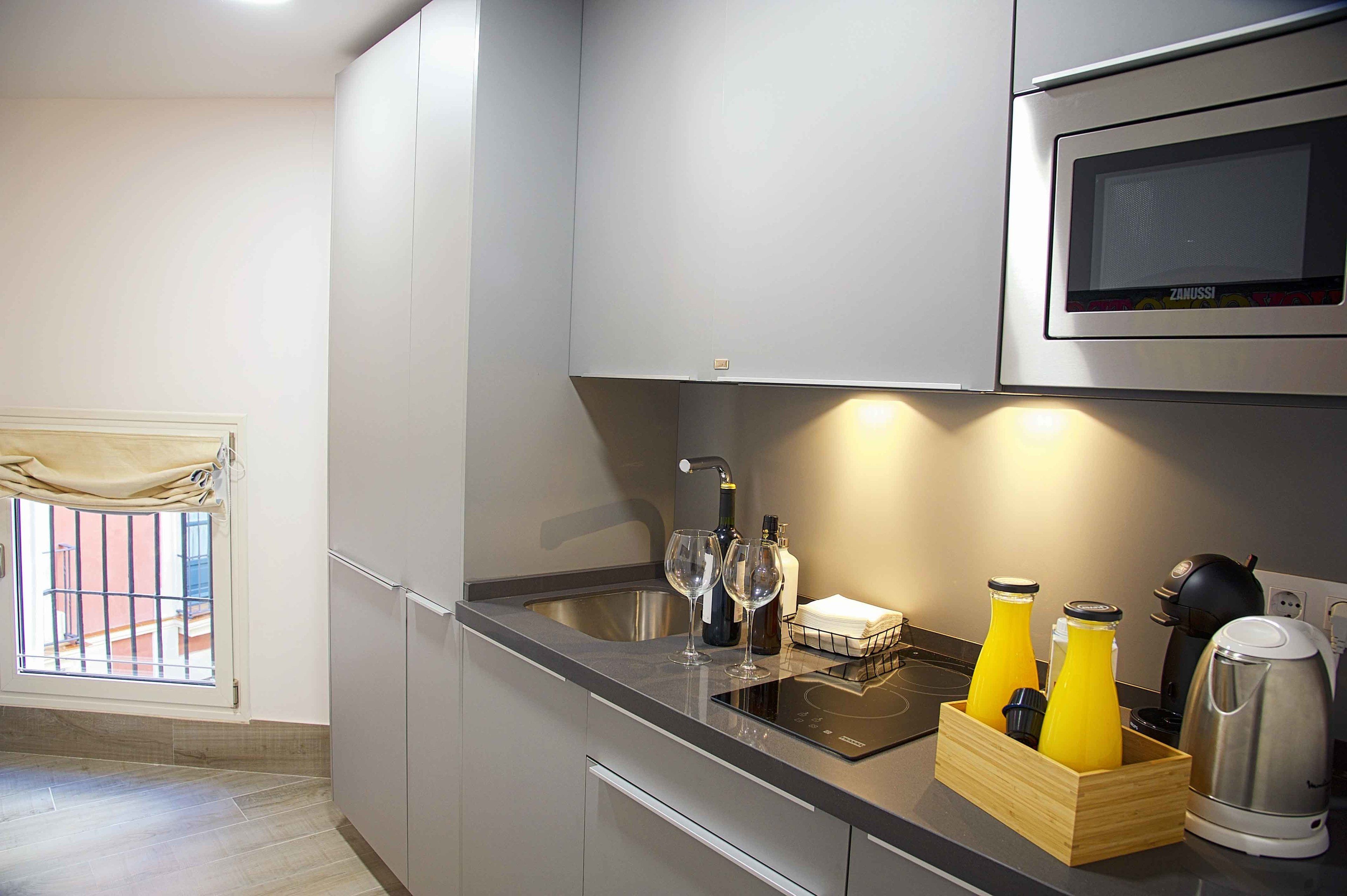 A modern kitchen with a built-in microwave, a sink, and a wooden wine cooler containing bottles.