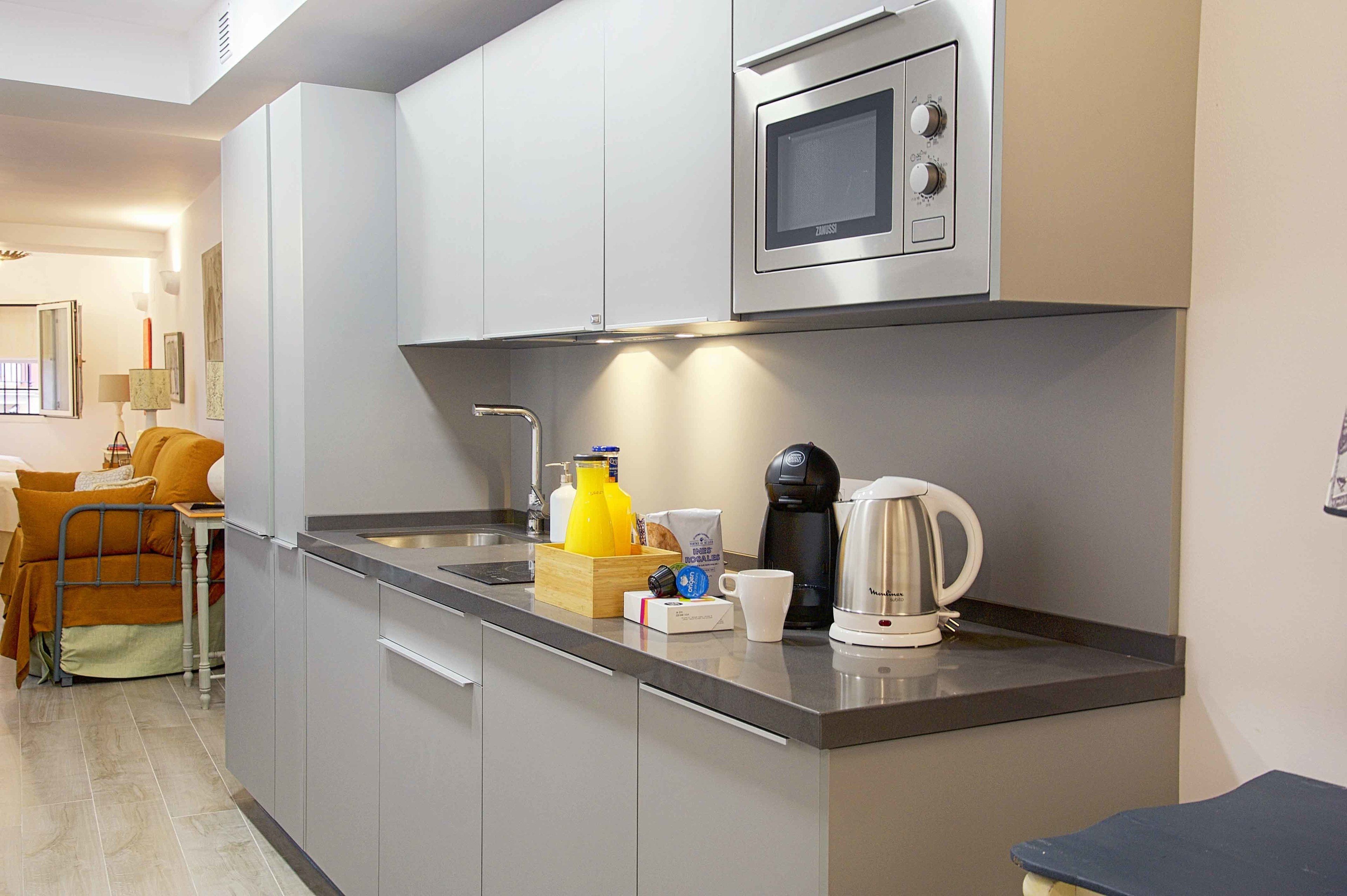 Una cocina moderna con microondas integrado, cafetera y lavabo.