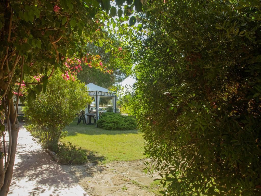 Un sentier de jardin mène à un belvédère agrémenté d’une table et de chaises, le tout entouré d’une végétation luxuriante.