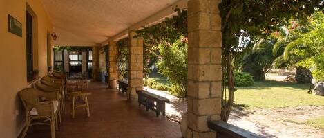 A covered outdoor area with stone pillars, wicker furniture, and a bench.