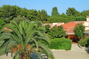 A villa with a red-tiled roof, surrounded by lush greenery and trees.