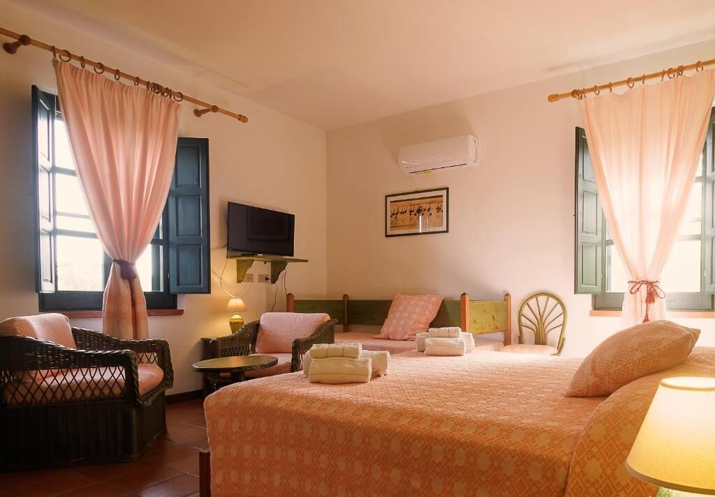 Ein Hotelzimmer mit einem Bett, zwei Sesseln, einem kleinen Tisch und einer Klimaanlage.