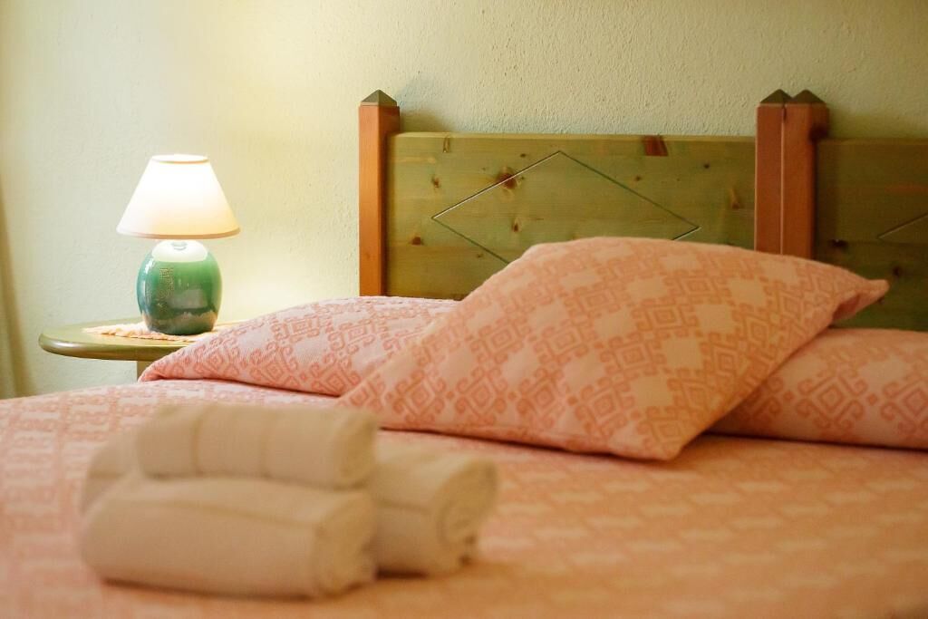 Una cama con ropa de cama estampada, un cabecero de madera y una lámpara de noche.