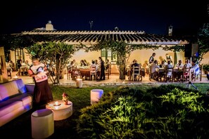 An outdoor dining area with tables and chairs, a covered seating area, and a building with a tiled roof.