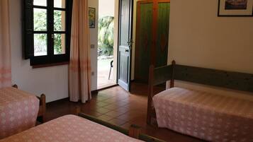 Una habitación con dos camas, una ventana con cortinas, una puerta y una mesita.