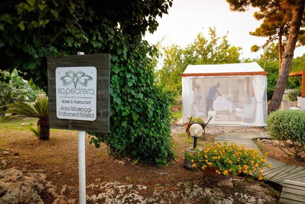 Segnale per 'sapedra Hotel & Restaurant' con area giardino, una struttura a forma di tenda e un vialetto.