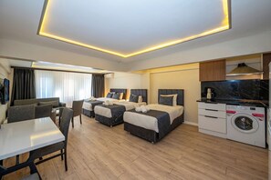 A hotel room with two beds, a dining area, a washing machine, and a television. - Aiza Suites (Istanbul)