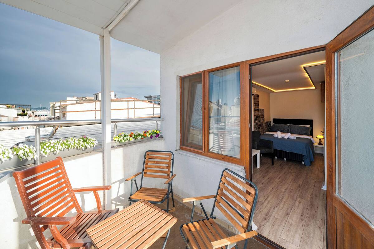 A balcony with wooden furniture and a view of the cityscape.