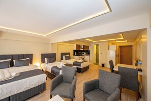 Habitación de hotel con dos camas, kitchenette y zona de estar.