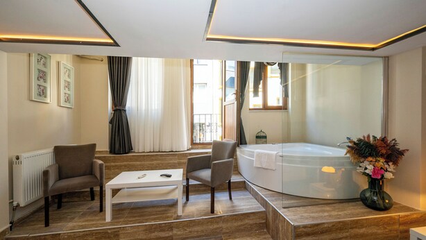 Un baño moderno con una bañera, una mesita, dos sillas y un florero.