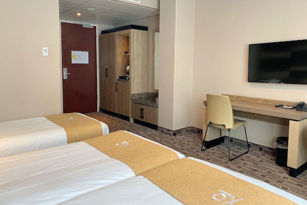 A hotel room with two beds, a desk, a chair, and a TV. - XO Hotels Blue Square (Amsterdam)
