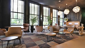 A spacious lobby with large windows, comfortable seating, and modern decor. - XO Hotels Couture (Amsterdam)