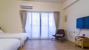 Une chambre d’hôtel avec deux lits, une chaise, une télévision et une petite table en bois.