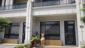 Un immeuble à plusieurs étages, doté d’un style architectural moderne, avec de grandes fenêtres et une entrée centrale agrémentée d’un banc en bois et d’une statue d’ours.