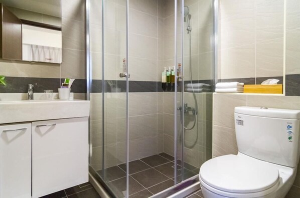Une salle de bain avec une douche à parois de verre, des toilettes et un lavabo avec un miroir au-dessus.