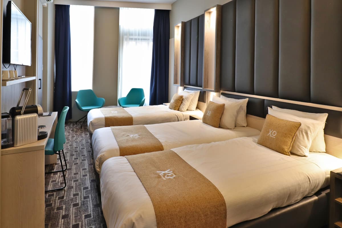 Een hotelkamer met twee bedden, een bureau, een stoel en een televisie.