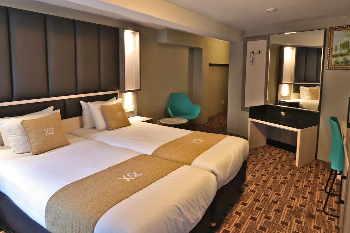 Een hotelkamer met een groot bed, een bureau, een stoel, een spiegel en een badkamer.