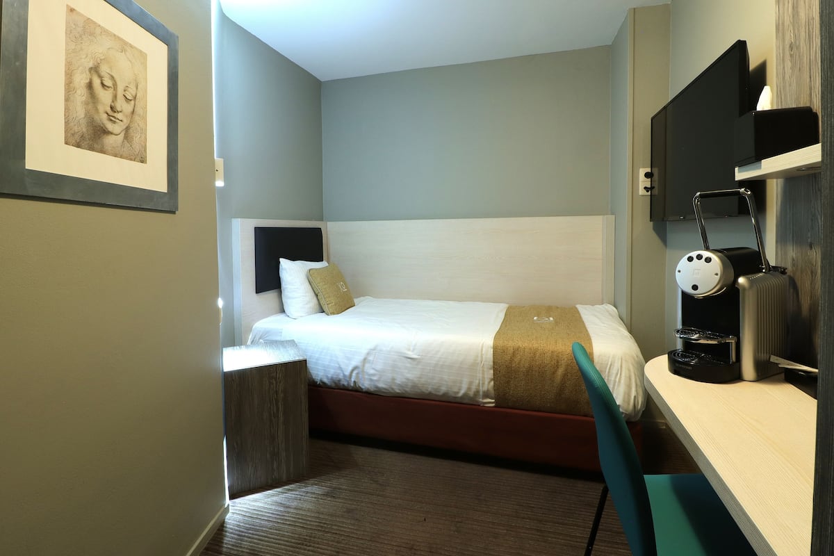 Een hotelkamer met een bed, nachtkastje en bureau met lamp.