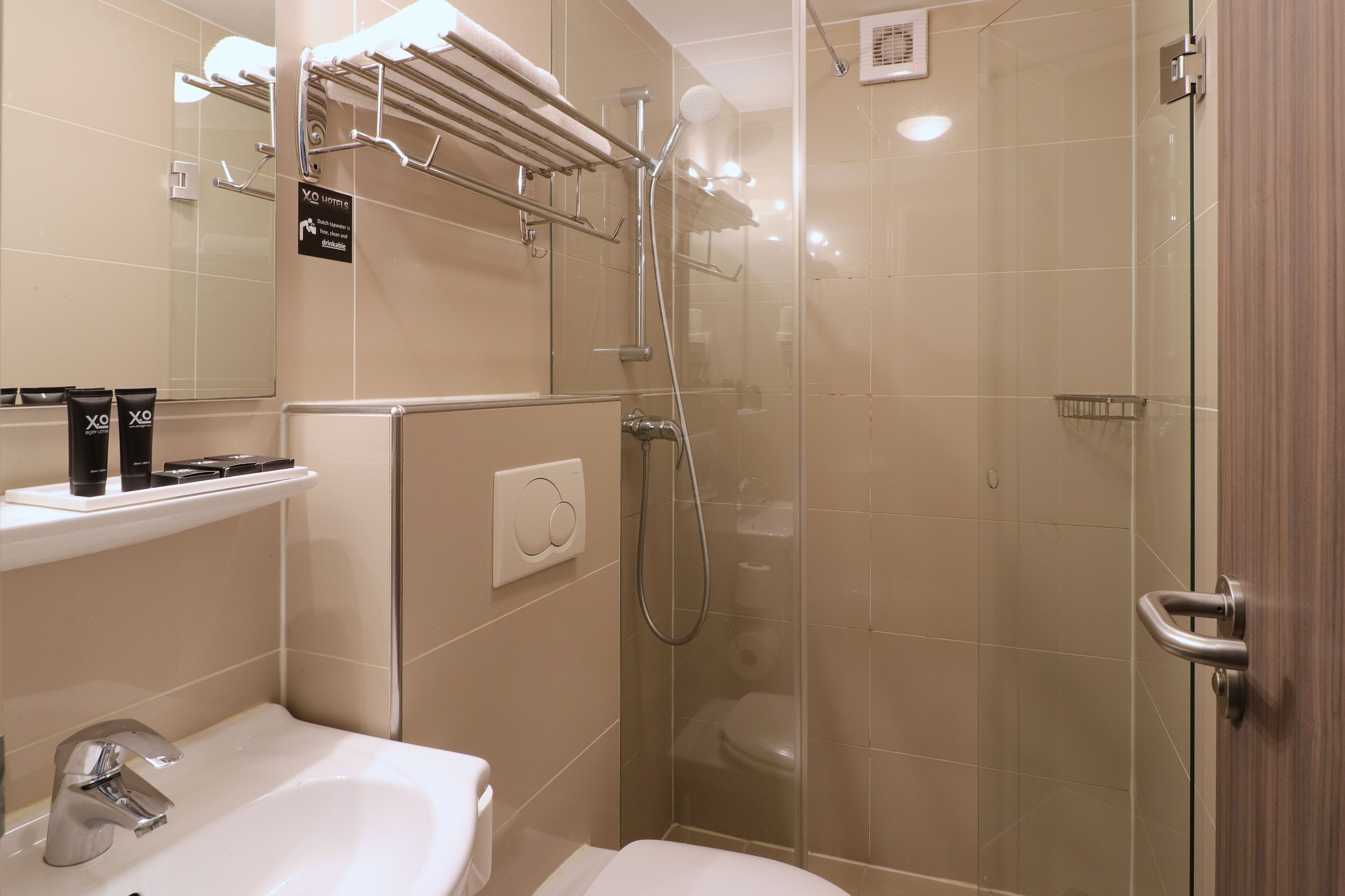 A modern bathroom with a glass-enclosed shower, a white sink, and a towel rack.