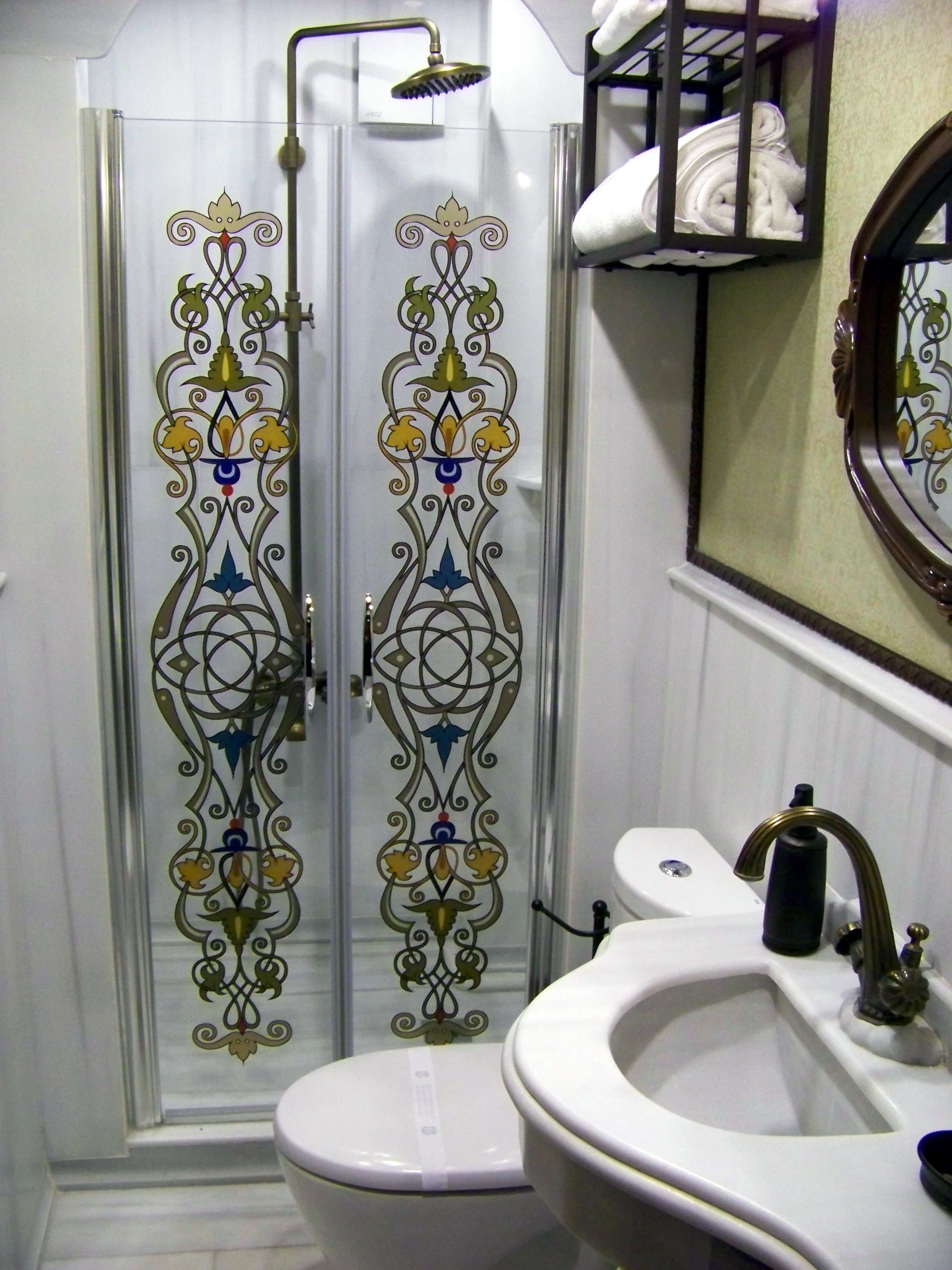 Un baño con mampara de vidrio, inodoro y lavamanos con espejo.